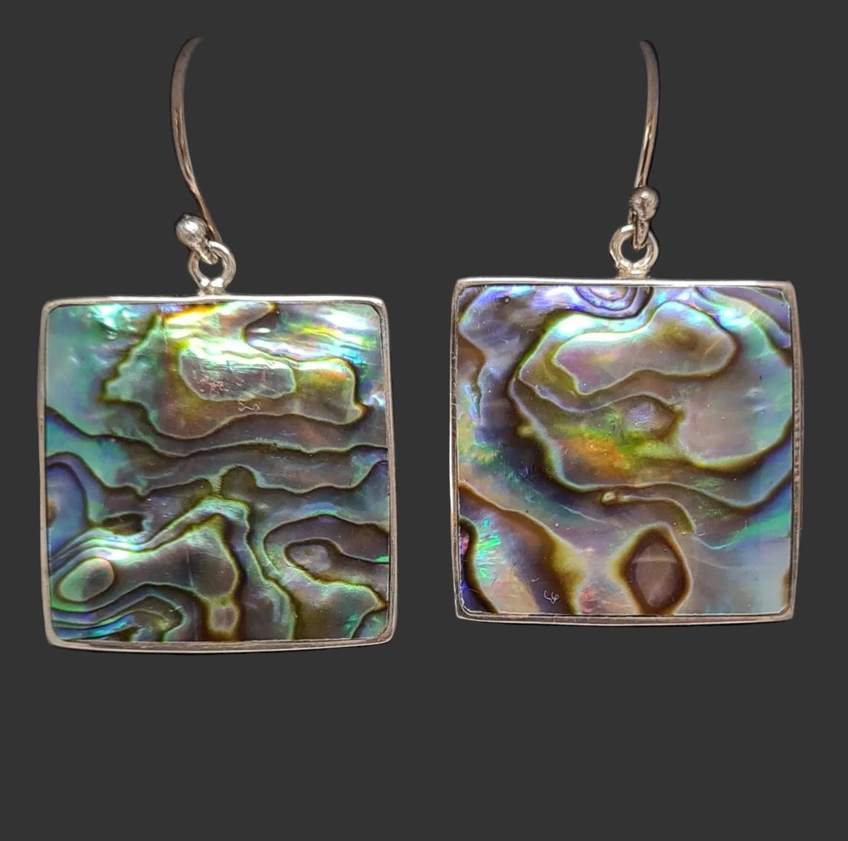 A pair of square drop earrings with iridescent abalone shell inlays and silver-tone hooks, displayed in a white jewelry box on a black insert with a handwritten price tag reading $12.